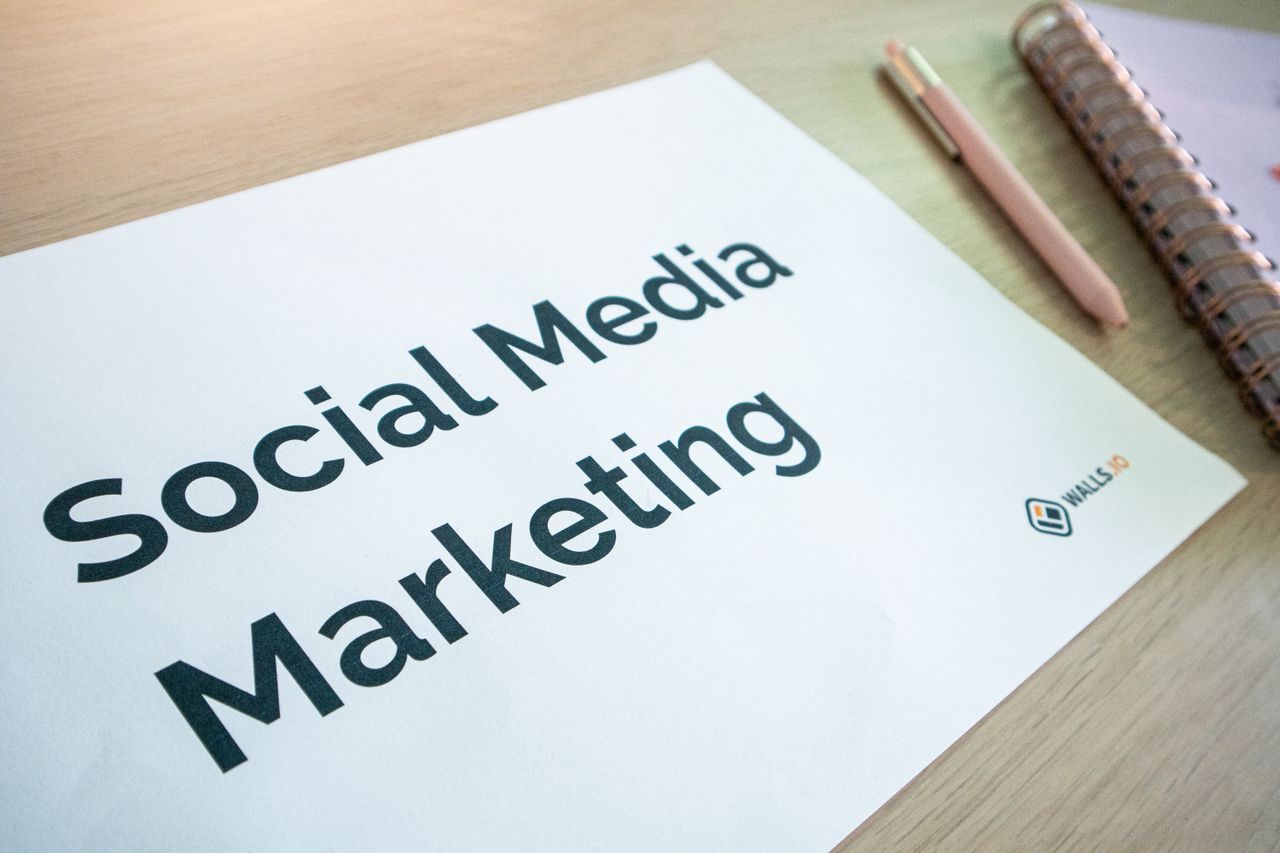 Detailní záběr na dokument o marketingu na sociálních sítích ležící na stole spolu s perem a zápisníkem.